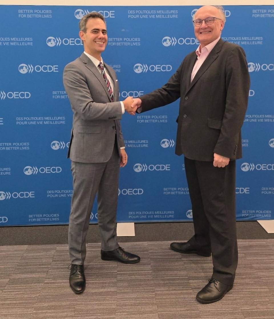 Guy Mor shaking hands with a senior official at an international OECD policy event.